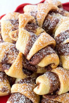 a red plate filled with pastries covered in powdered sugar on top of a table