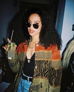 a woman holding a drink in her right hand and wearing sunglasses on top of her head