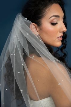 a woman wearing a wedding veil with pearls on the back of her head and shoulder