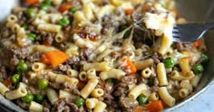 a close up of a bowl of food with pasta and vegetables in it, with a fork