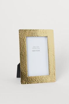 a gold frame with a black stand on the bottom and a white background behind it