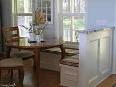 a kitchen table with two chairs and a bench in front of the window next to it