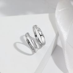 two wedding rings sitting on top of a white surface