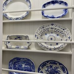 blue and white plates are on shelves in a room with white paneled walls,