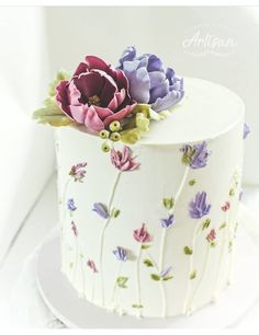 there is a white cake with flowers on the top and bottom layer, decorated with purple and pink flowers