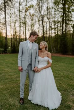 a bride and groom standing together in the grass