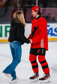 a man and woman standing on top of an ice rink holding each other's hands