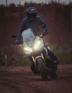 a man riding on the back of a white motorcycle down a dirt road at night