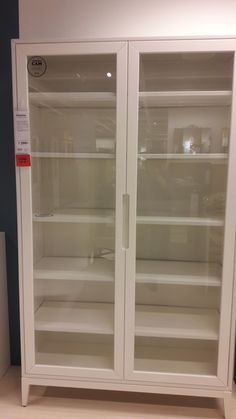 an empty glass doored cabinet in a room with wood flooring and blue walls