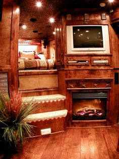 a living room with a fireplace and tv on the wall, surrounded by wood paneling