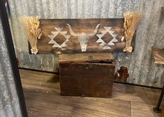 a wooden sign with an image of a cow skull on it and some wheat stalks