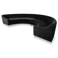 a black curved couch sitting on top of a white floor