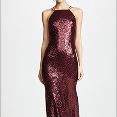 a woman wearing a long red sequin dress with halter neck and open back