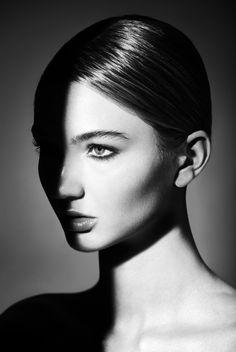 a black and white photo of a woman's face with her hair pulled back