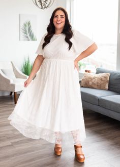 Brooke is 5'6" and wearing a size smallAshley is 5'5" and wearing a size 2x - Runs TTS with an elastic waistband for comfortable fit - Beautiful white lace overlay across the whole dress - Slight flutter sleeve shape to make it easy to move in - Keyhole in the back to make it easy to put on and take off - Available in sizes S-3X Product Measurements*Measurements are taken from side seam to side seamwhile laying flat. Small: Length: 51" Bust: 17" Waist: 14"Medium: Length: 51.5" Bust: 18" Waist: 1 Modest Lace Dress With Lace Sleeves, Flowy Lace Midi Dress With Lace Trim, Flowy Lace Midi Dress With Short Sleeves, Flowy Midi Dress With Lace Trim For Casual Wear, Modest Lace Maxi Dress For Spring, Modest White Dress With Lace Trim, White Dress With Elastic Waistband For Brunch, Feminine White Dress With Elastic Waistband, White Feminine Dress With Elastic Waistband