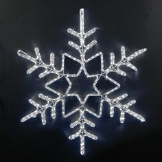 a lighted snowflake on a black background with white lights in the shape of a star