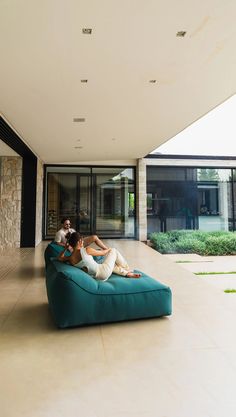 two people sitting on a large blue couch in the middle of an open floor plan