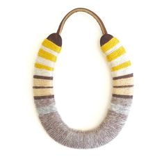 a necklace made out of wool and leather with two different colors on the front, one is