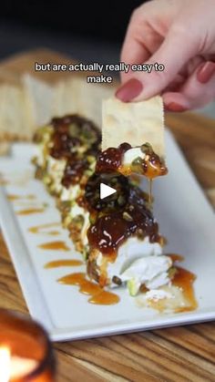 someone is dipping some kind of food on top of a white plate with crackers