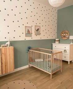 a baby's room with polka dot wallpaper and wooden crib in the corner