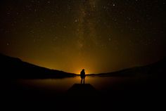 a person standing on a dock looking up at the night sky