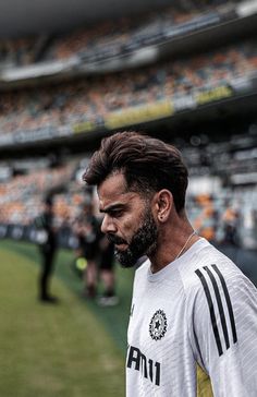 a man with a beard standing in front of a soccer ball on the field at a stadium