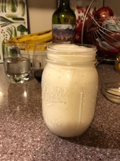 a mason jar filled with liquid sitting on top of a counter next to bowls and glasses