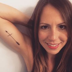 a woman with a small arrow tattoo on her left arm and right arm behind her head