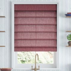 a kitchen window with roman shades in grey