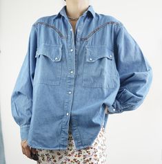 Vintage 90s Denim Western Shirt with Detailed Trim  Embrace the timeless charm of Western wear with this vintage denim shirt featuring intricate trim detail. Perfect for adding a touch of rugged elegance to your wardrobe, this shirt is both versatile and stylish. Features: *Era: 90s *Size: Marked M (please refer to measurements) *Material: 100% Cotton Denim *Color: Light Wash Blue *Details: Button-down front, long sleeves with buttoned cuffs, pointed collar, Western yoke with detailed trim, dual Western Style Washed Tops For Spring, Blue Shirt For Spring Rodeo, Vintage Long Sleeve Denim Top For Spring, Light Wash Tops For Rodeo In Spring, Blue Shirt For Rodeo In Spring, Vintage Medium Wash Denim Top For Fall, Vintage Denim Blue Top For Spring, Light Wash Denim Tops For Rodeo, Spring Denim Shirt For Rodeo