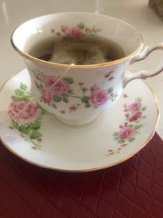 a tea cup filled with green tea and pink roses