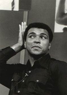 a black and white photo of a man holding his hands up to his ears with one hand