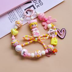 a bunch of beads that are on top of a pink book page next to a pair of scissors