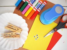 craft supplies laid out on a table with scissors, markers and paper plates next to them