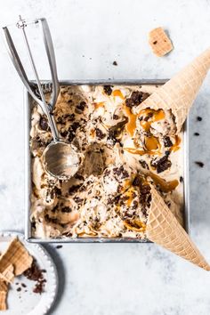 an ice cream sundae in a metal pan with spoons and graham crackers