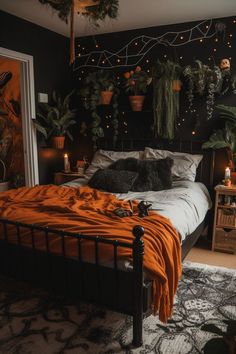 a bed with an orange blanket and some potted plants on the wall above it