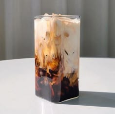 an iced drink in a glass with ice and coffee on the bottom, sitting on a table