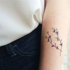 a woman's arm with a small flower tattoo on the left side of her arm