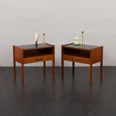 two small wooden tables sitting next to each other on top of a black flooring