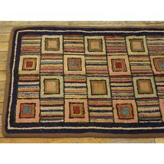 a rug on the floor with squares and stripes in blue, pink, green, yellow and brown colors