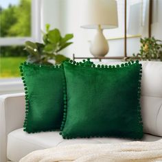 two green pillows sitting on top of a white couch