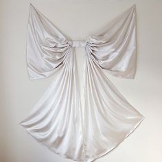 a white wall hanging on the side of a room with curtains pulled back and tied together