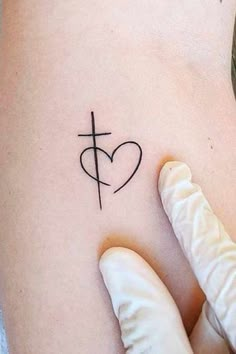 a woman's arm with a cross and heart tattoo on it