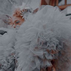 a woman wearing a white dress with ruffles on it's shoulders and head