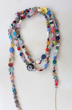 a multi - colored beaded necklace is displayed on a white surface with a tassel