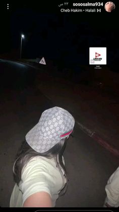 a person wearing a white hat on top of their head in the street at night