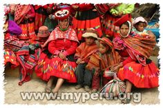 a group of people sitting next to each other on the ground in colorful clothing and hats