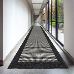 a long hallway with a black and white rug on the floor next to large windows