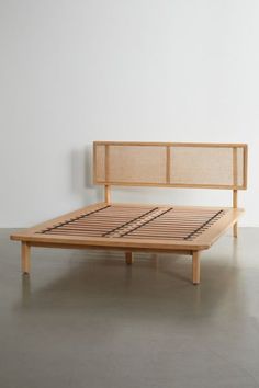 a wooden bed frame sitting on top of a cement floor next to a white wall