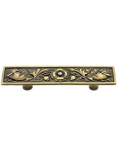 an ornate brass drawer pull with flowers on it